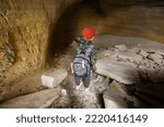 Boy wear backpack explore limestone stone cave at mountain in Pidkamin, Ukraine.