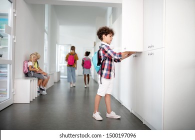 Boy Wearing Backpack. Schoolboy Wearing Backpack Putting Things Inside Locker At The End Of School Day