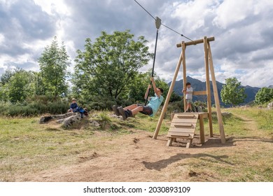 Boy Wearing A Face Mask Jumps Off A Playground Zip Line In Summer Camp As Others Look At Him, Horizontal