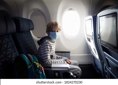 Boy Wearing Face Mask Sitting In Airplane Cabin, Travel During Coronavirus Pandemic Concept