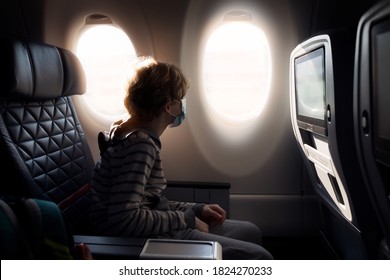 Boy Wearing Face Mask Sitting In Airplane Cabin, Travel During Coronavirus Pandemic Concept