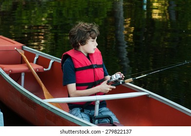 Boy Wearing A Lifejacket Fishing In A Canoe