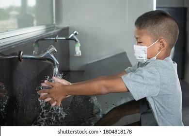 Boy Wearing A Mask Washing Hands In Public Toilets.