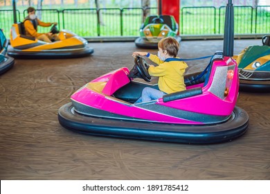 Boy Wearing A Medical Mask During COVID-19 Coronavirus Having A Ride In The Bumper Car At The Amusement Park