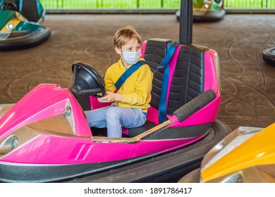 Boy Wearing A Medical Mask During COVID-19 Coronavirus Having A Ride In The Bumper Car At The Amusement Park