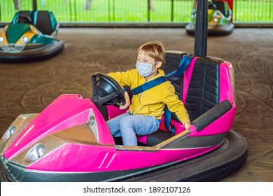 Boy Wearing A Medical Mask During COVID-19 Coronavirus Having A Ride In The Bumper Car At The Amusement Park