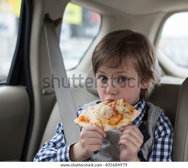 boy wearing safety car belt and eating pizza\
margarita in the car