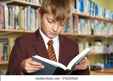 Boy Wearing School Uniform Reading Book In Library