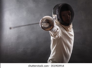 Boy wearing white fencing costume and black fencing mask standing with the sword practicing in fencing. - Powered by Shutterstock