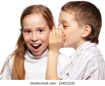 El chico susurra a la chica en el secreto del oído. Chismes de los niños