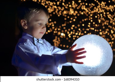 boy in a white shirt holds in hands glowing ball.