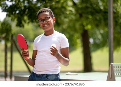 A boy in a white tshirt playing table tennis