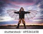 Boy with wings at sunset imagines himself a pilot and dreams of flying