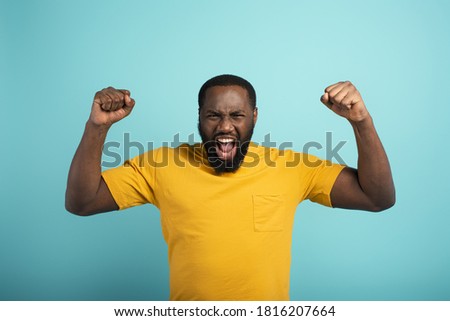 Similar – Cheerful man celebrating his success with a broad smile and raised fist in front of a neutral background