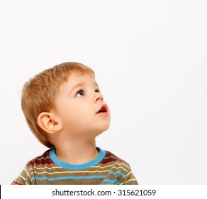 Boy in winter clothes looking up on white background