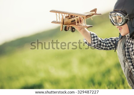 Boy with wooden airplane in the field