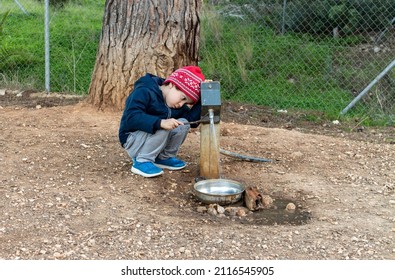 Boy In Woolen Cap Opening Water Tap In Dog Drinking Trough