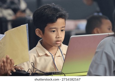 A boy working on a coding project on his laptop while taking part in a coding competition.