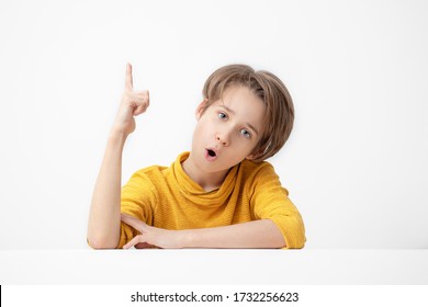 boy in yellow  pointing up with one finger,  isolated on white background, teenager pointing a great idea and asks to looking up