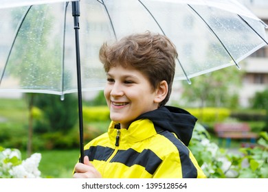 Boy in yellow raincoat holds transparent Umbrella during the rain. Rainy weather at spring, summer - Shutterstock ID 1395128564