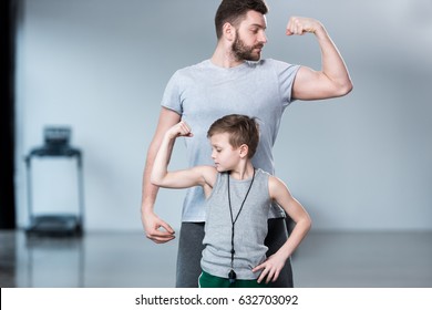 Boy with young man, his trainer or father showing muscles 