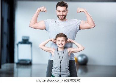 Boy with young man, his trainer or father showing muscles 
