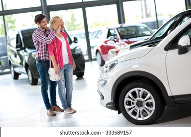 
Boyfriend Covering The Eyes Of His Girlfriend For A Surprise In Car Showroom