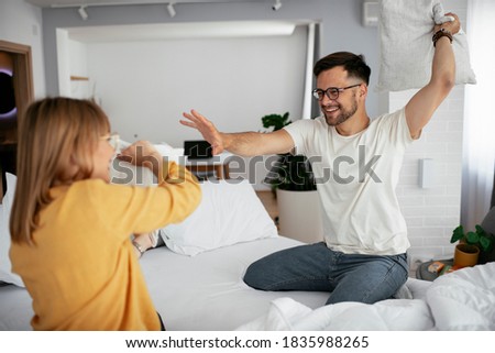 Boyfriend and girlfriend fighting pillows on the bed. Happy couple having fun at home.	


