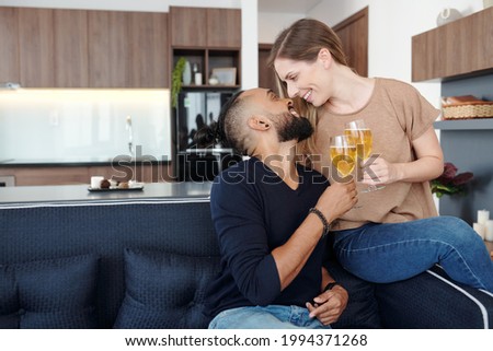 Boyfriend and girlfriend spending evening at home, drinking wine, looking at each other and almost kissing
