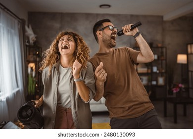 Boyfriend sing on microphone while girlfriend hold loudspeaker karaoke - Powered by Shutterstock