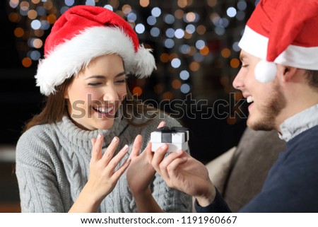 Boygriend giving a gift to his partner on christmas sitting on a couch in the living room at home