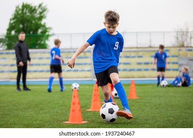 Boys attending soccer training on school field. Young man coaching children on physical education class. Soccer practice for children