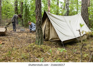 Boys Building A Fire In A Fire Pit Made Out Of Bucket Near The Tent In The Forest. Starting A Campfire- Starting A Fire Using A Fire Striker- Bushcraft And Primitive Skills.