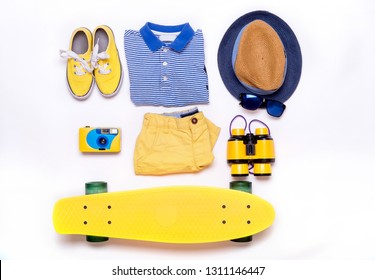 Boy's Casual Outfits - Sneakers, Striped Shirt, Hat, Binoculars, Sun Glasses, Camera, Skateboard. Essential Vacation Items For Traveler. Top View. Kids Summer Travel Background. Flat Lay Clothes.