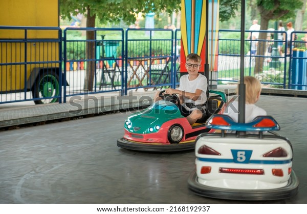 Boys driving\
cars in an amusement park. Have fun weekend at the theme park.\
Children competing on mini car\
racing