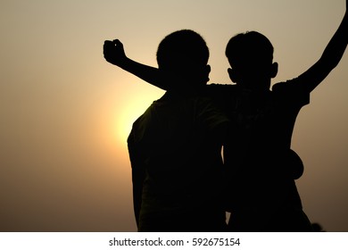 Boys embrace with friends to feel their joy after the victory. silhouette, sunset