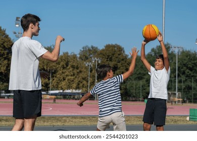 Boys engage in outdoor basketball training with a coach, practicing dribbling, passing, and shooting skills on a court surrounded by greenery under bright natural light, fostering teamwork  - Powered by Shutterstock