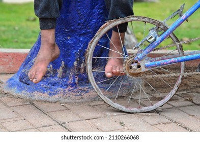 Boy's Feet With Old And Broken Bicycle Wheel.