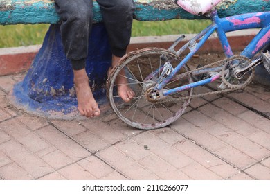 Boy's Feet With Old And Broken Bicycle Wheel.