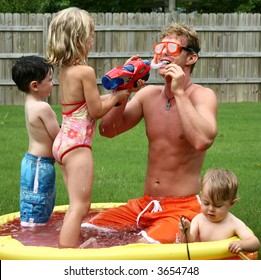 Boys And Girl With Dad In The Kiddie Pool.