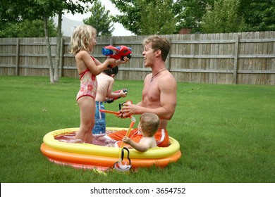 Boys And Girl With Dad In The Kiddie Pool.