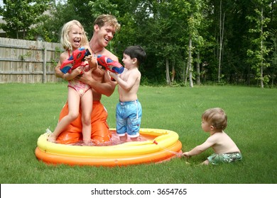 Boys And Girl Play With Dad In The Kiddie Pool With Water Guns