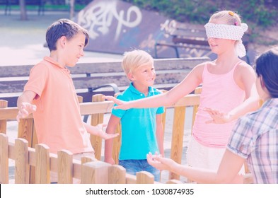 Boys with girlfriends are playing in blindfolders on the playground.
