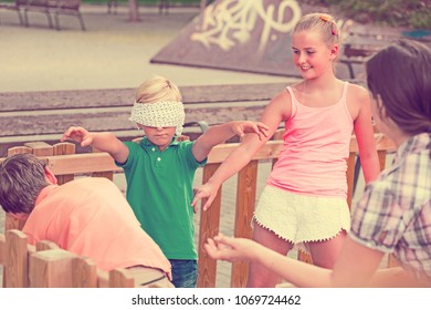 Boys with girlfriends are playing in blindfolders on the playground.