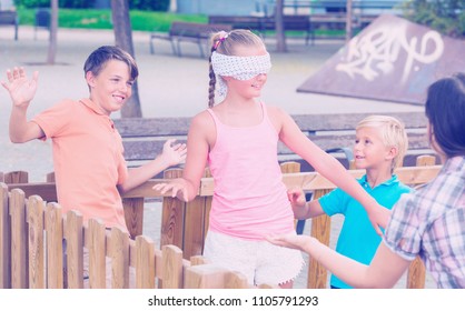 Boys with girlfriends are playing in blindfolders on the playground.