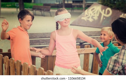 Boys with girlfriends are playing in blindfolders on the playground.
