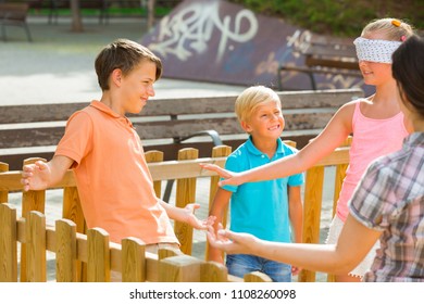 Boys with girlfriends are playing in blindfolders on the playground.