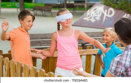 Boys with girlfriends are playing in blindfolders on the playground.