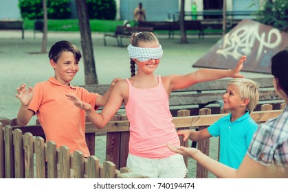 Boys with girlfriends are playing in blindfolders on the playground.