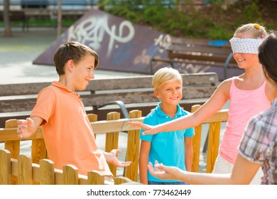 Boys with girlfriends are playing in blindfolders on the playground.